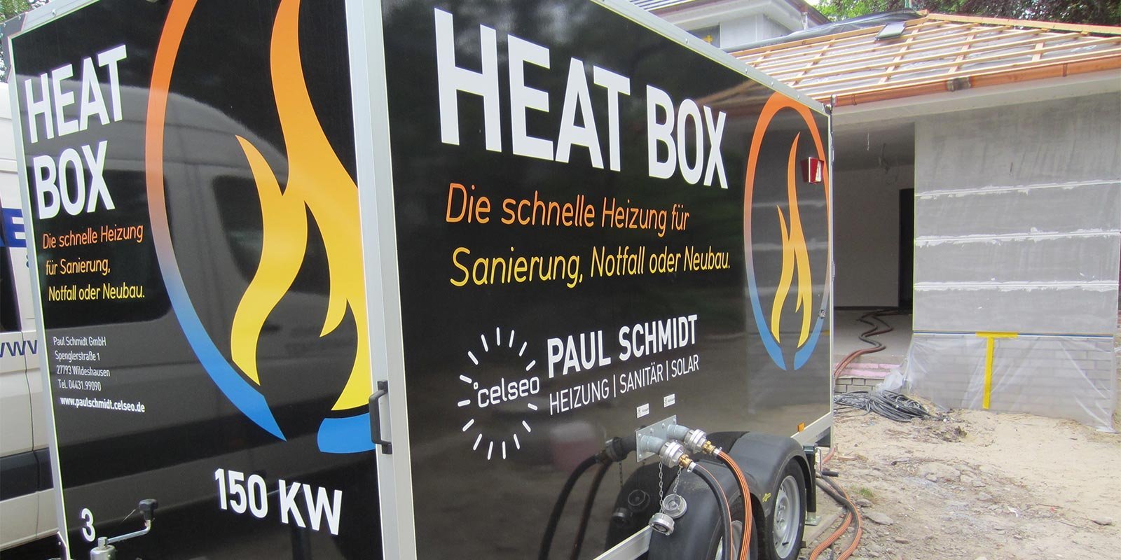 Ein Heizcontainer mit der Aufschrift 'HEAT BOX' steht vor einem im Bau befindlichen Gebäude, um schnelle Heizlösungen anzubieten.