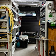 Ein geräumiger Transporter zeigt eine Vielzahl von Werkzeugen, Eimern und Kabeln, die ordentlich auf Regalen angeordnet sind.