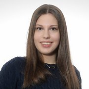 Eine junge Frau mit langen, glatten Haaren lächelt freundlich in die Kamera, während sie einen blauen Pullover trägt.