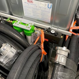 Eine Anordnung von schwarzen Schläuchen, die ordentlich gebündelt sind, mit einem grünen und silbernen Ventil in der Mitte.